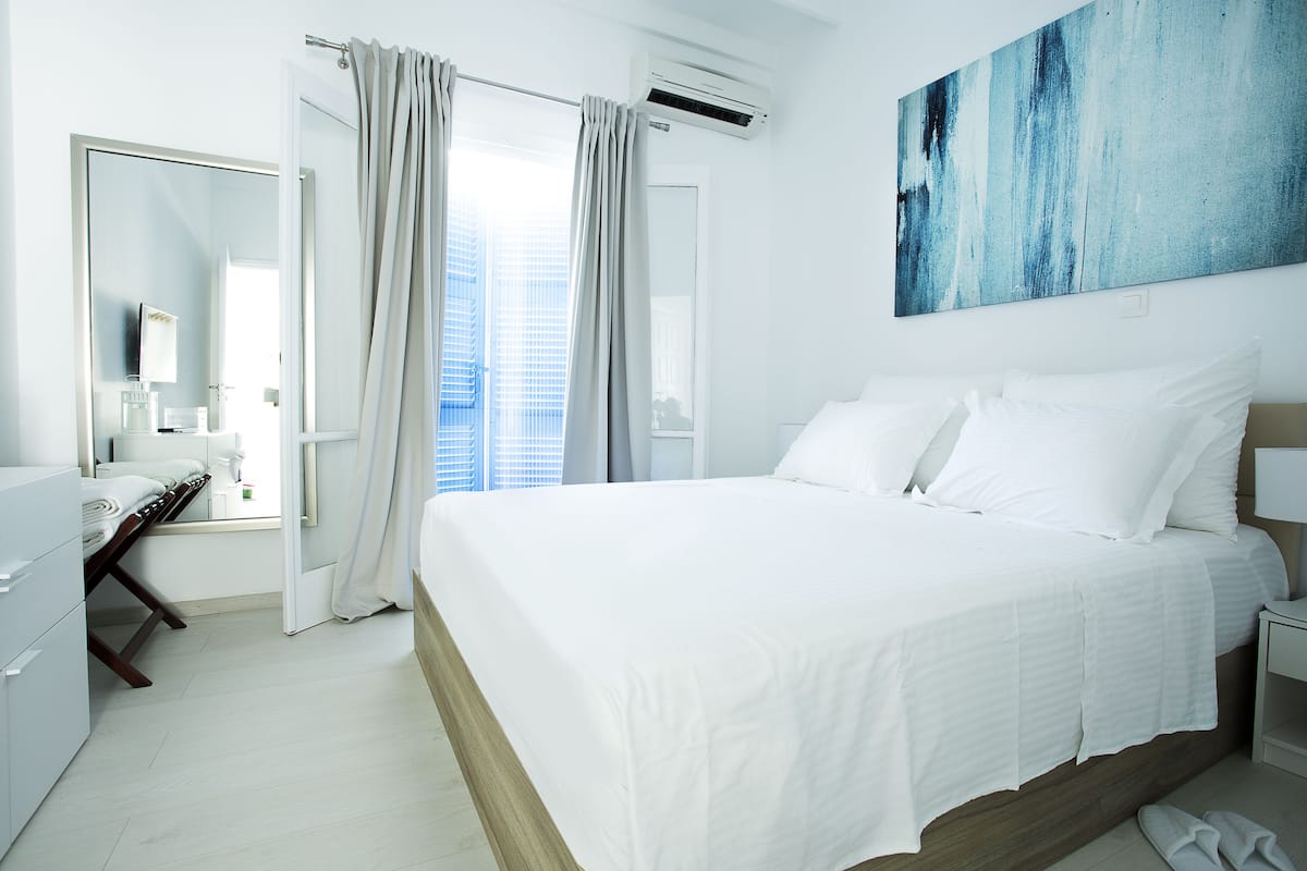 A modern hotel room with a large bed, a desk, and a view of the city.