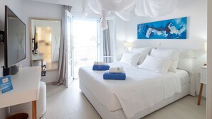 A hotel room with a large bed, a TV, a desk, and a window with curtains. - Sun n Chill (Corfu)