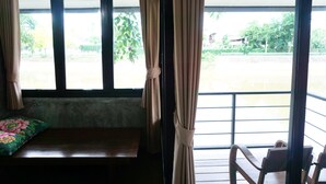 A room with a bench, a window with curtains, and a view of greenery outside. - R-Lampang Guest House (Lampang)