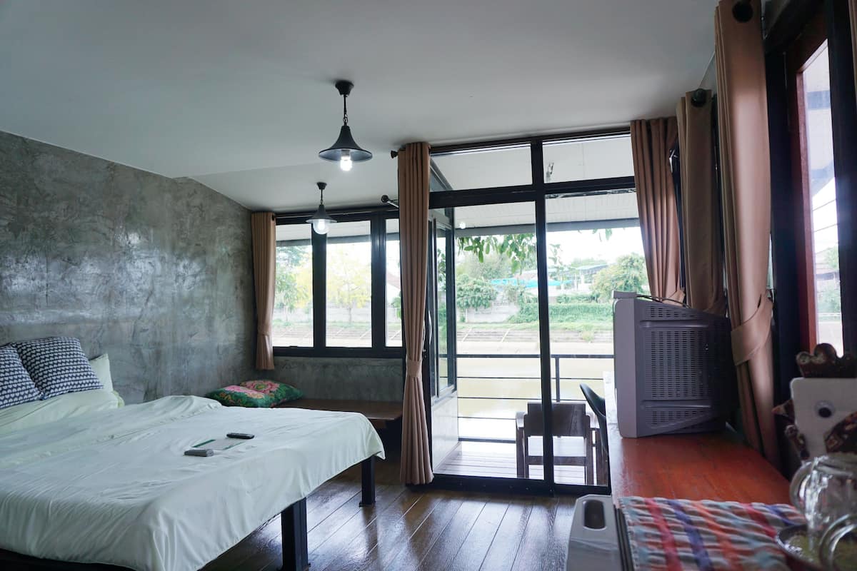 Une chambre à coucher avec un lit, un banc, une table et une fenêtre avec des rideaux.