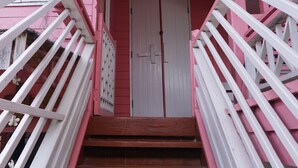A staircase with pink railings leading to a white door. - R-Lampang Guest House (Lampang)