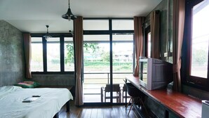 A room with a bed, a desk, a television, and large windows. - R-Lampang Guest House (Lampang)