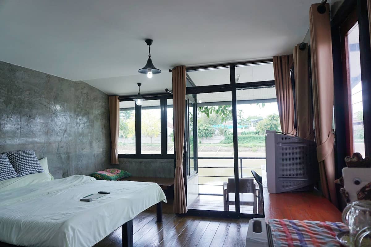 Une chambre à coucher avec un lit, un bureau, une chaise, un téléviseur et une fenêtre avec des rideaux.