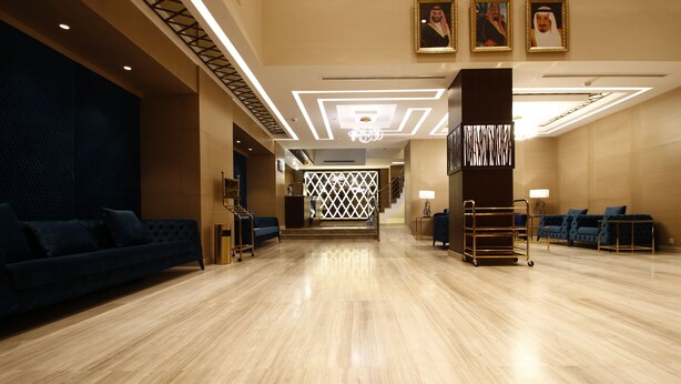 A spacious lobby with a polished wooden floor, a blue sofa, and a reception desk. - Diwan Residence Hotel  Alsalamah (Jeddah)