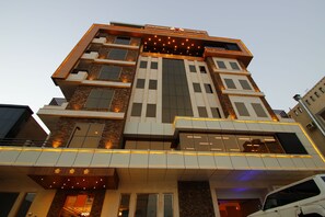 Un hotel de varios pisos con un diseño arquitectónico moderno, que destaca por una entrada imponente con fachada de vidrio y señalización iluminada.