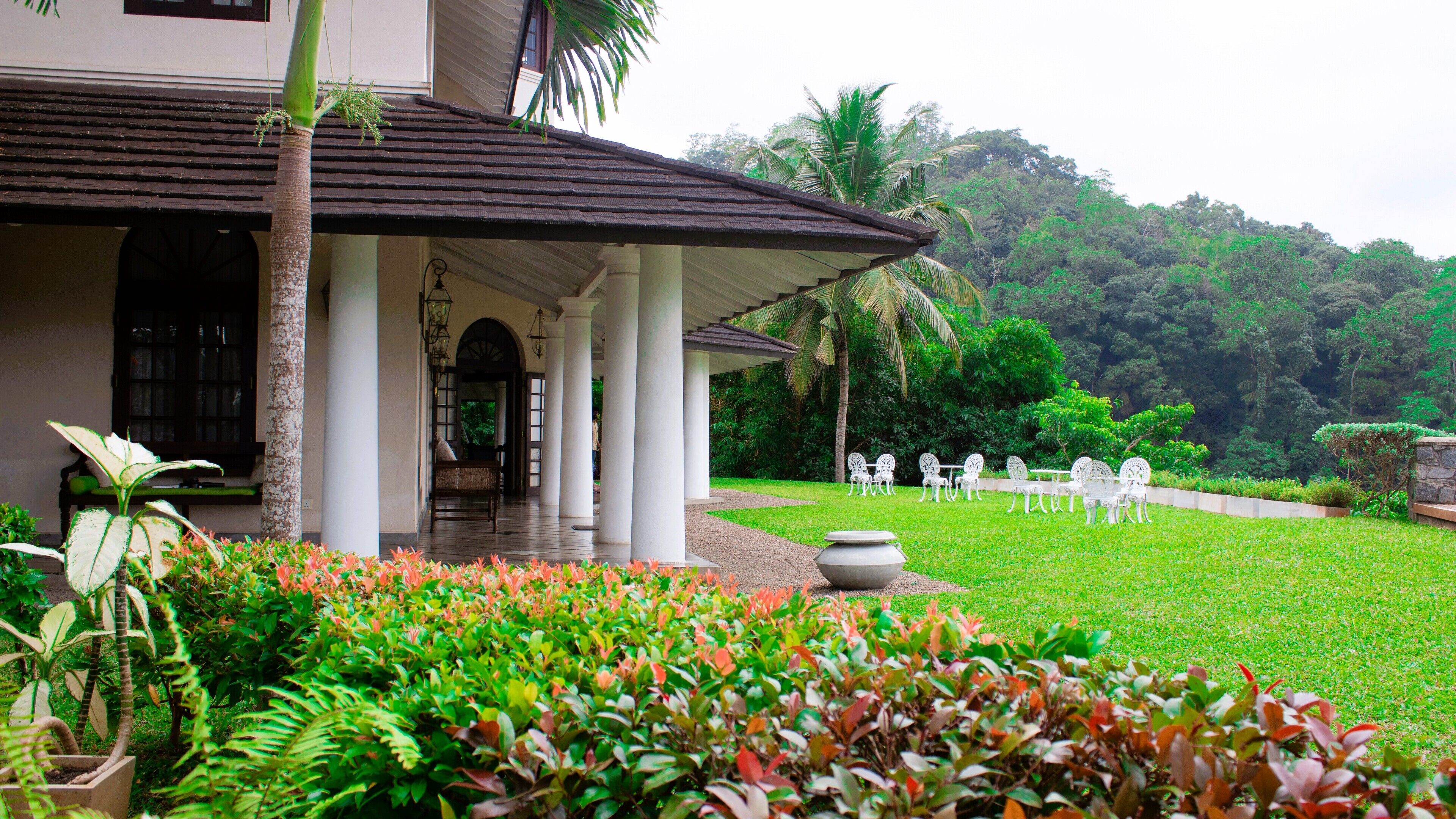 A covered outdoor area with a seating arrangement and a pathway leading to a building entrance.