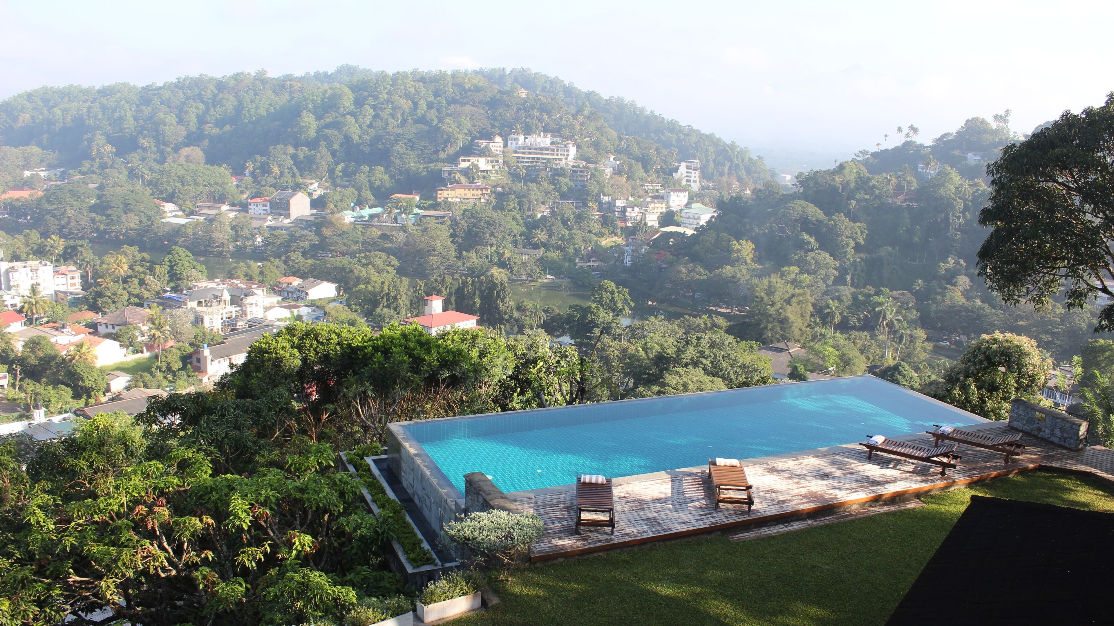 A swimming pool with lounge chairs and a view of a hillside town.