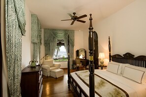A four-poster bed with a canopy, a sitting area with a chair and a small table, and a view of the outdoors through a window. - Coffee Bungalow Kandy (Kandy)