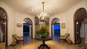 A room with a round table, two chairs, a chandelier, and a view of the outdoors. - Coffee Bungalow Kandy (Kandy)