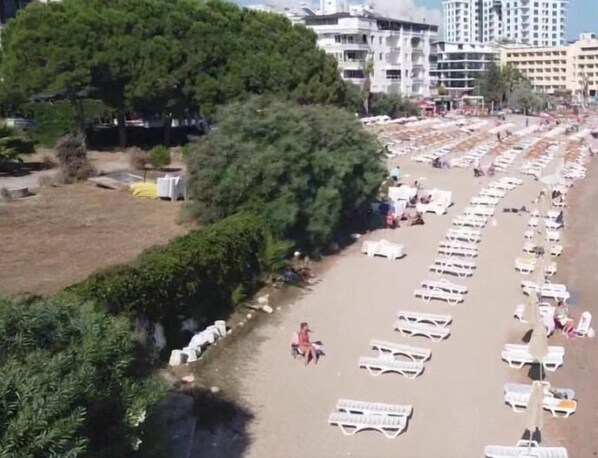 A beach with rows of sun loungers and a few people walking. - Hotel Holiday Apart (Didim)