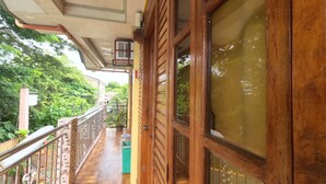 A wooden balcony with a tiled floor, a metal railing, and a view of greenery. - Woodside Rogers Residence (Puerto Princesa)