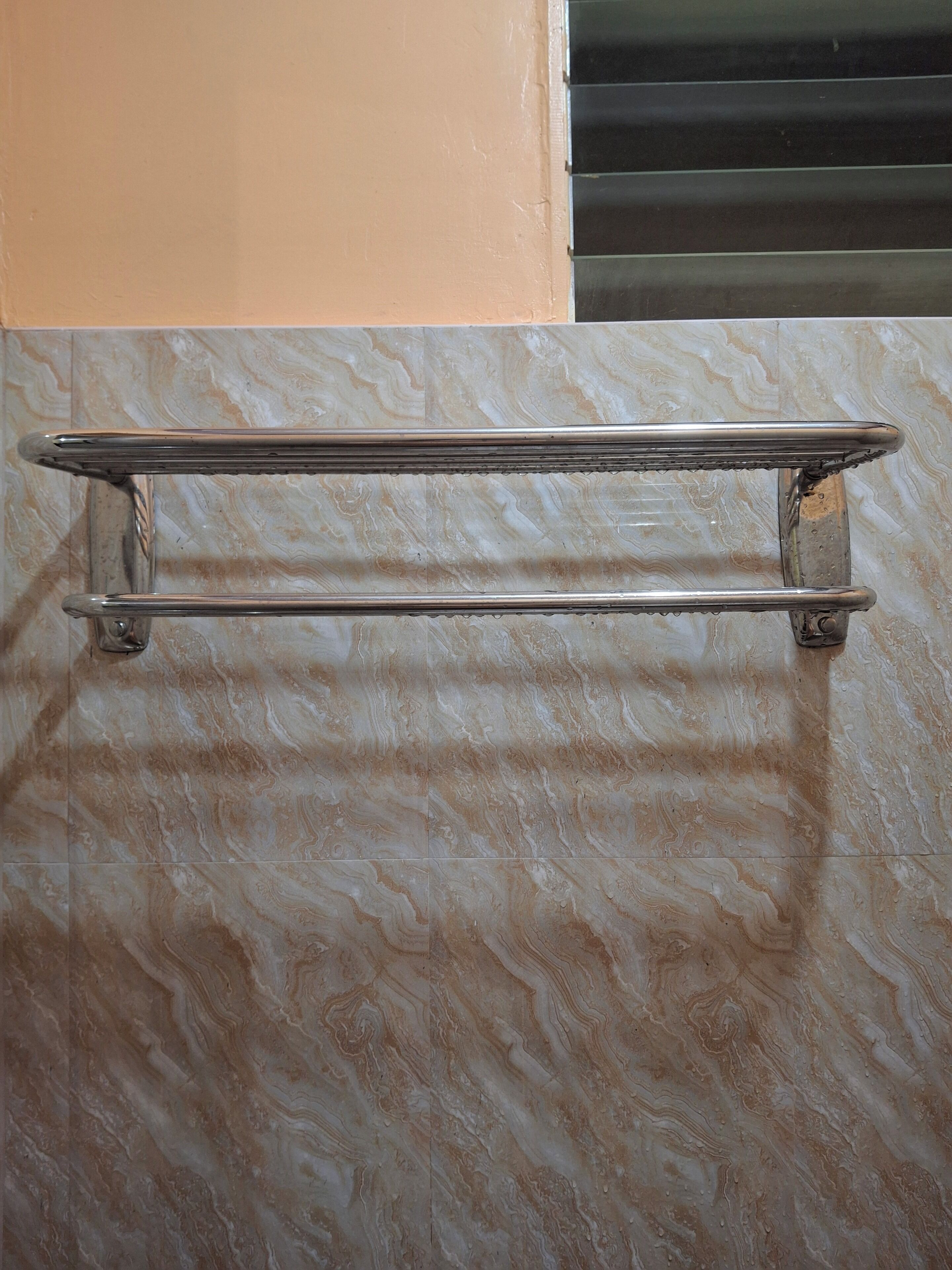 A metal towel rack mounted on a wall with a marble-like pattern.