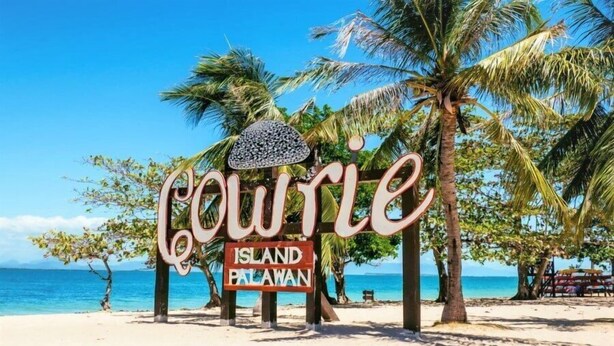 A beach sign with the name "Coulter Island Palawan" and palm trees in the background. - Woodside Rogers Residence (Puerto Princesa)