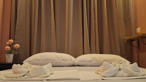 A hotel room with a bed, white pillows, and a neatly made bed with towels. - Woodside Rogers Residence (Puerto Princesa)