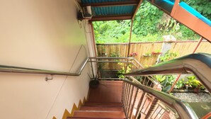 A staircase with metal railings and wooden steps leading to a covered area with greenery visible outside. - Woodside Rogers Residence (Puerto Princesa)