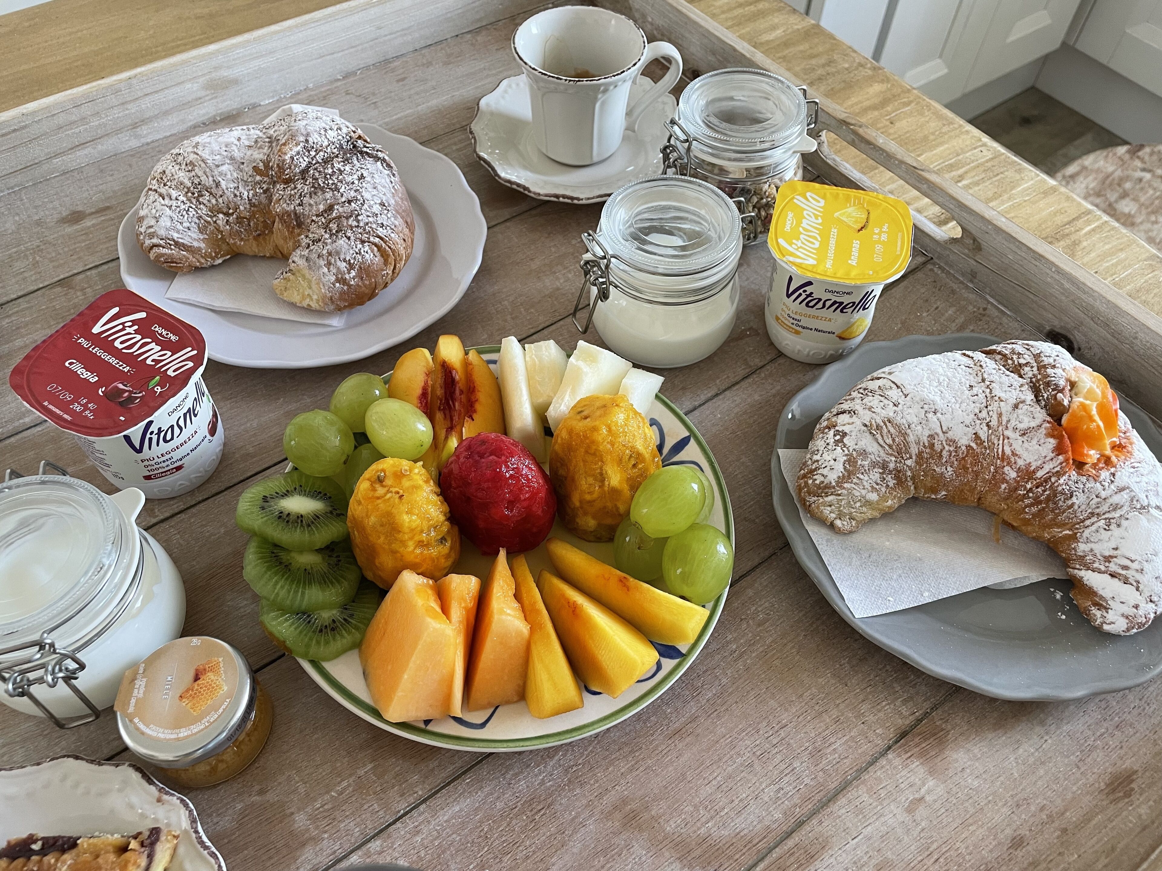 Ein Frühstückstisch mit Croissants, Obst, Joghurt und Honig.