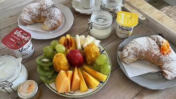 Ein Frühstückstisch mit Croissants, Obst, Joghurt und Honig.