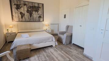 A bedroom with a bed, a chair, a wardrobe, and a world map on the wall.