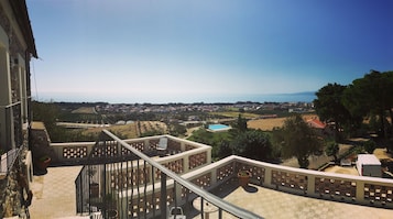 Un balcón con vistas a una zona residencial, una piscina y un cuerpo de agua lejano.