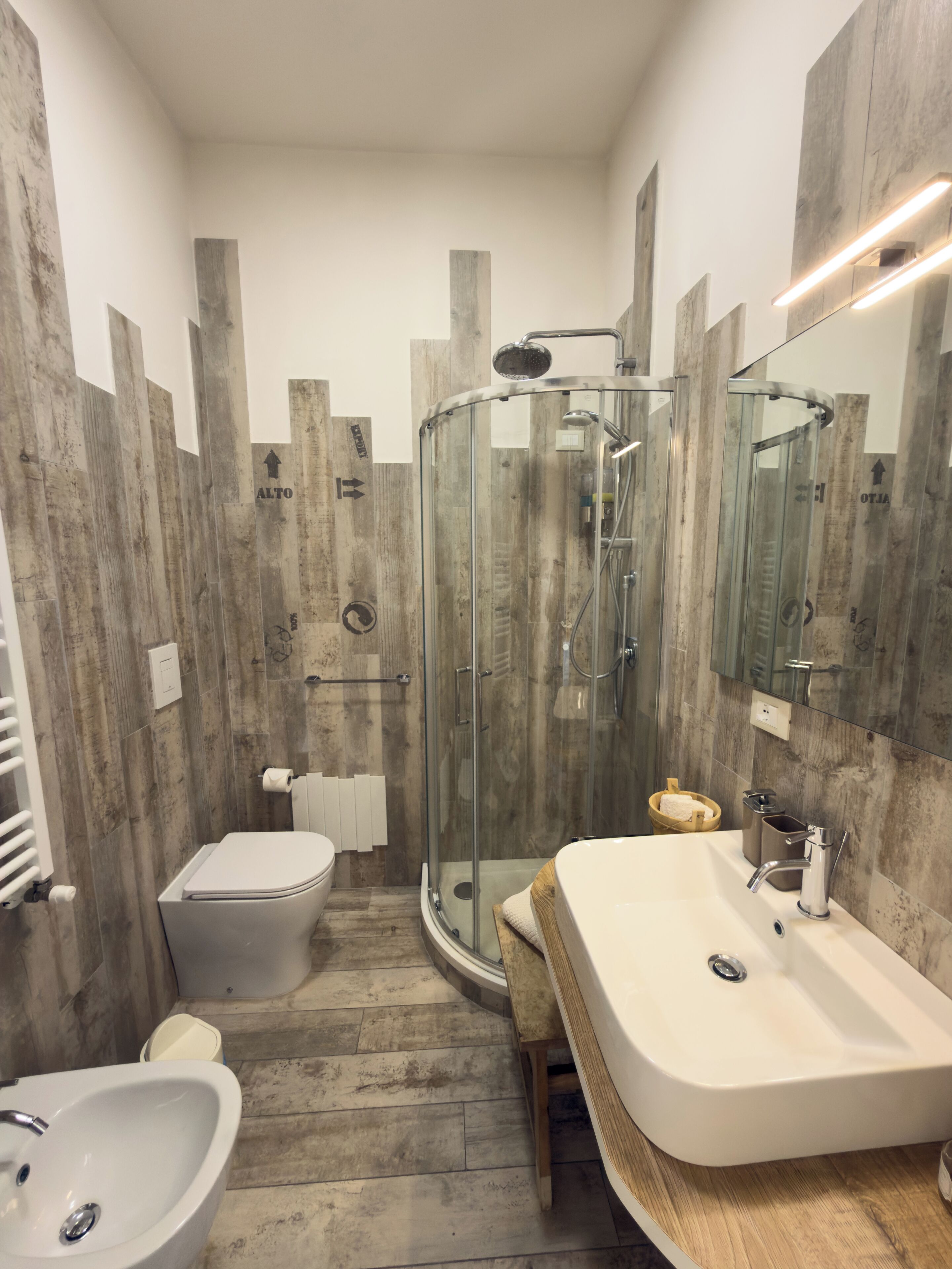 A bathroom with a glass shower enclosure, a white sink, and a toilet.