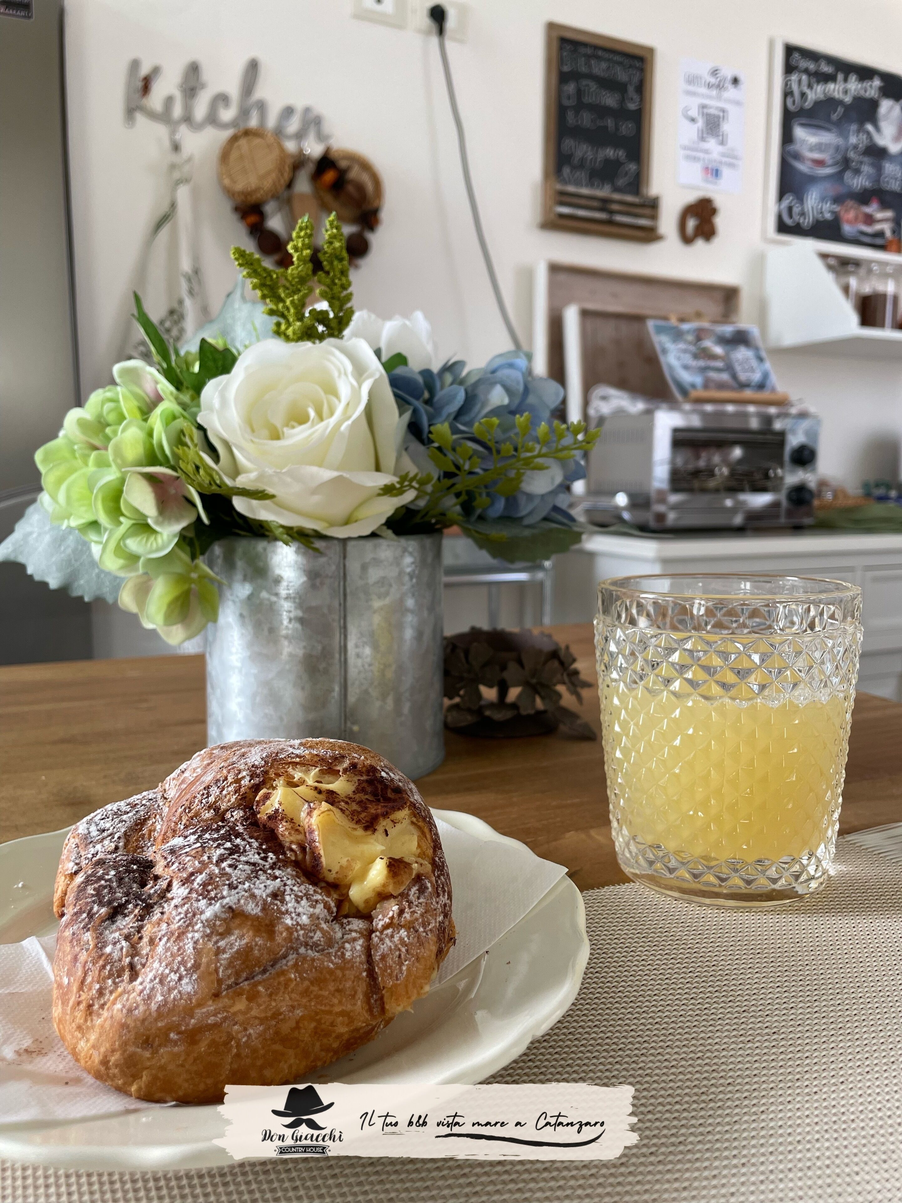 A kitchen area with a white wall, a flower vase, a toaster, and a plate with a pastry.