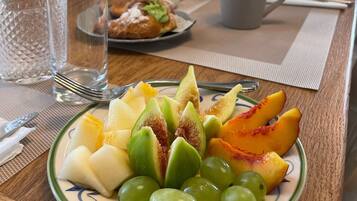 Una mesa de desayuno con un plato de fruta, una jarra y una taza.