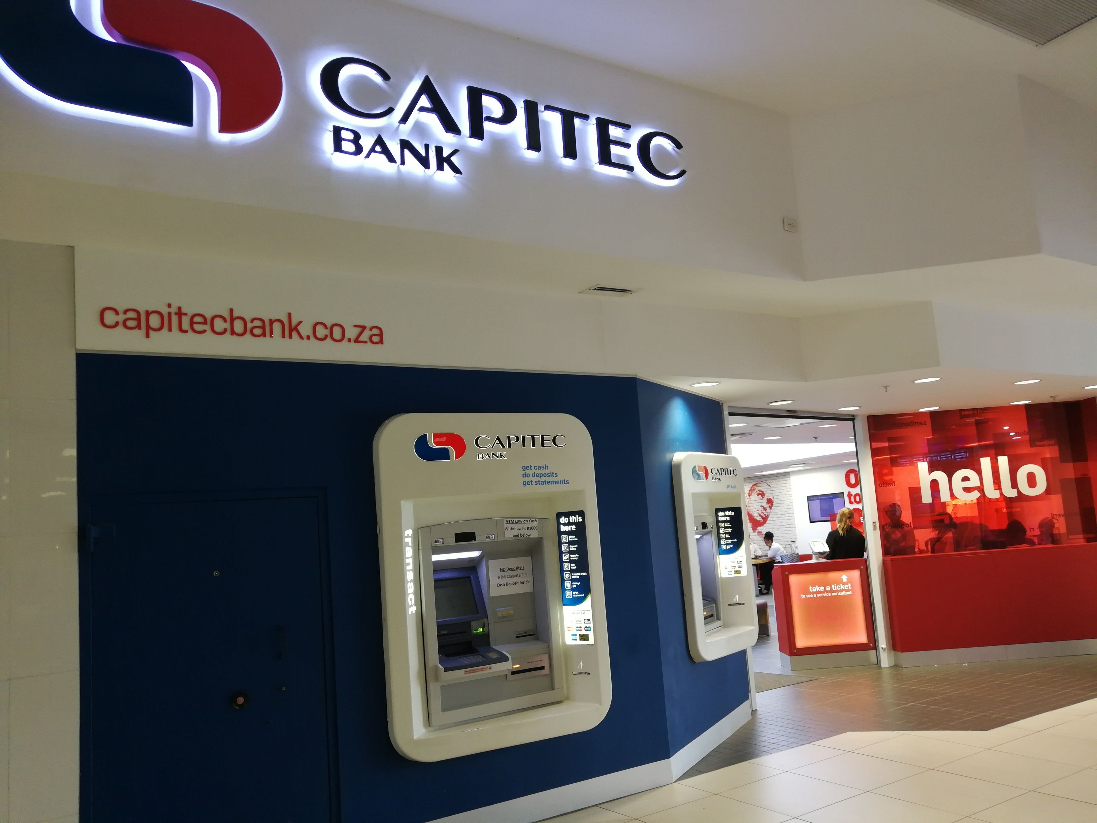 Eine Filiale der Capitec Bank mit Geldautomaten und einem Schild mit der Aufschrift 'hello'.