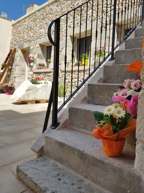 Un bâtiment en pierre avec un escalier menant à une porte. Des compositions florales sont disposées sur les marches.