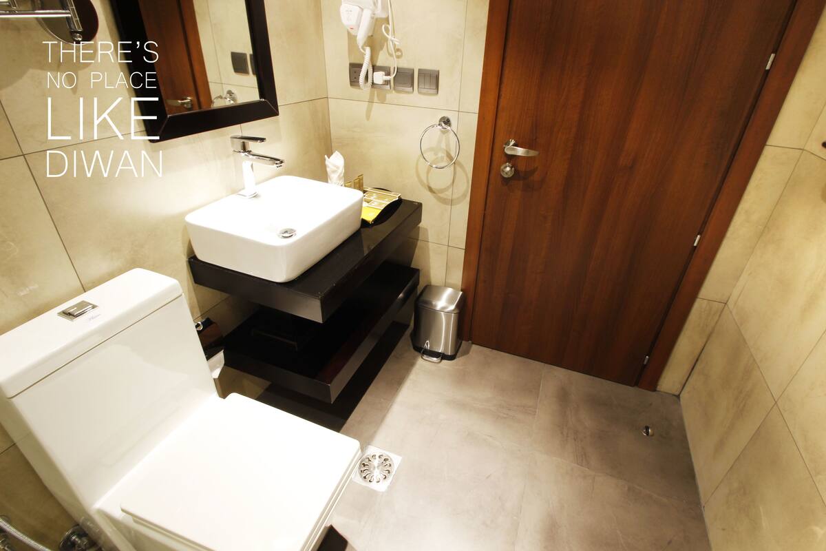 A modern bathroom with a white sink, a toilet, a mirror, and a shower area.
