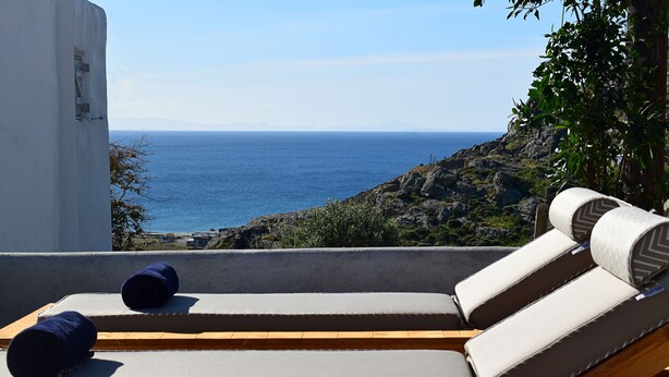 A sun lounger with cushions, overlooking a rocky coastline and the sea. - Livadi House Mykonos (Mykonos)