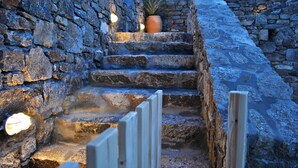 A stone staircase with a potted plant at the top, surrounded by stone walls and wooden railings. - Livadi House Mykonos (Mykonos)