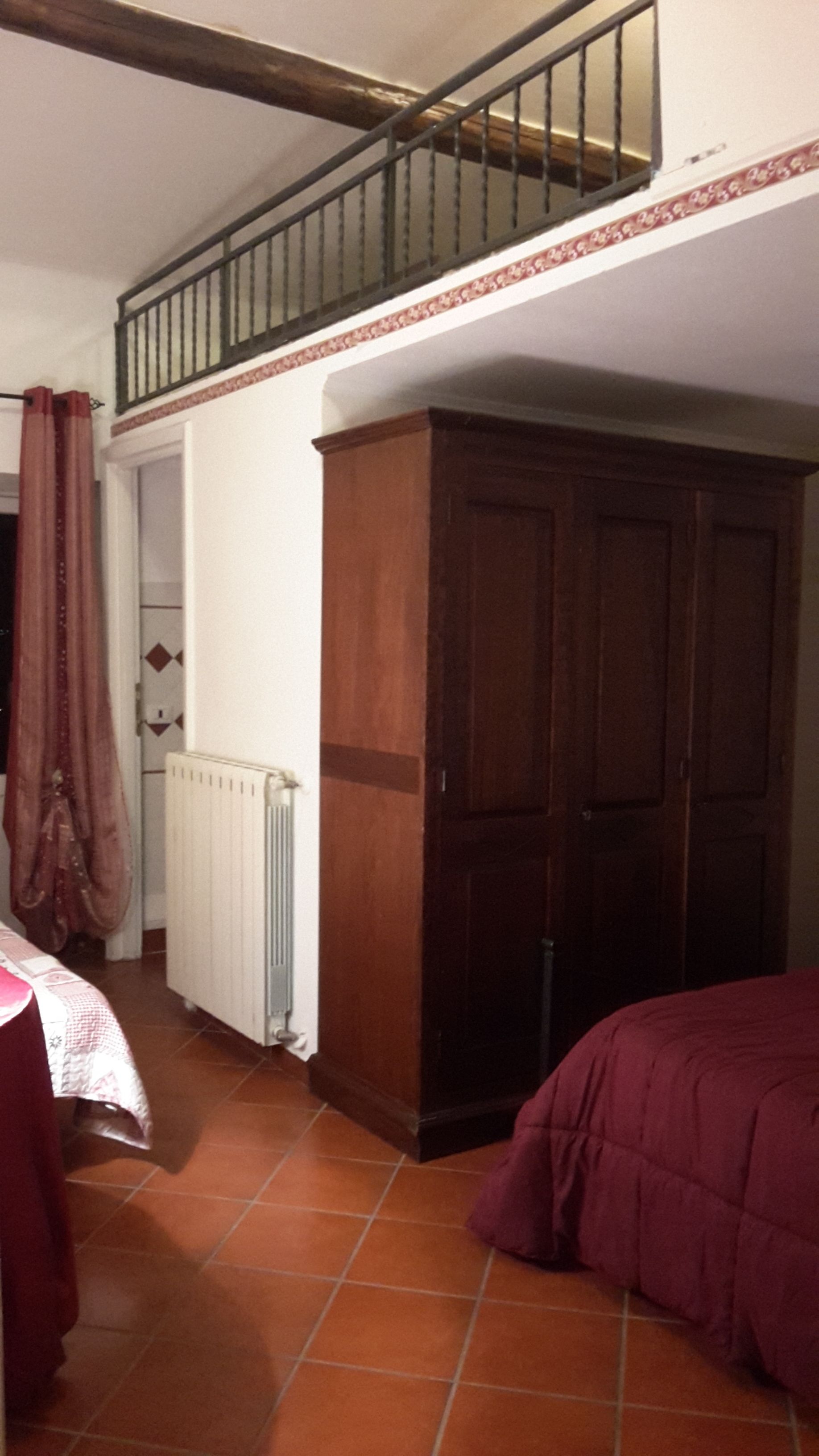 A bedroom with a bed, a radiator, a wardrobe, and a staircase.