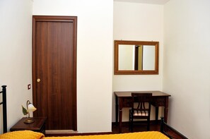 Una habitación con puerta de madera, un escritorio con silla y un espejo en la pared.