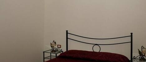 Una habitación con una cama, una mesita de noche con lámpara y una escalera.