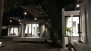 Ett modernt hus med en glasfasad, en täckt uteplats och en trappa som leder upp till ett andra våningsplan.