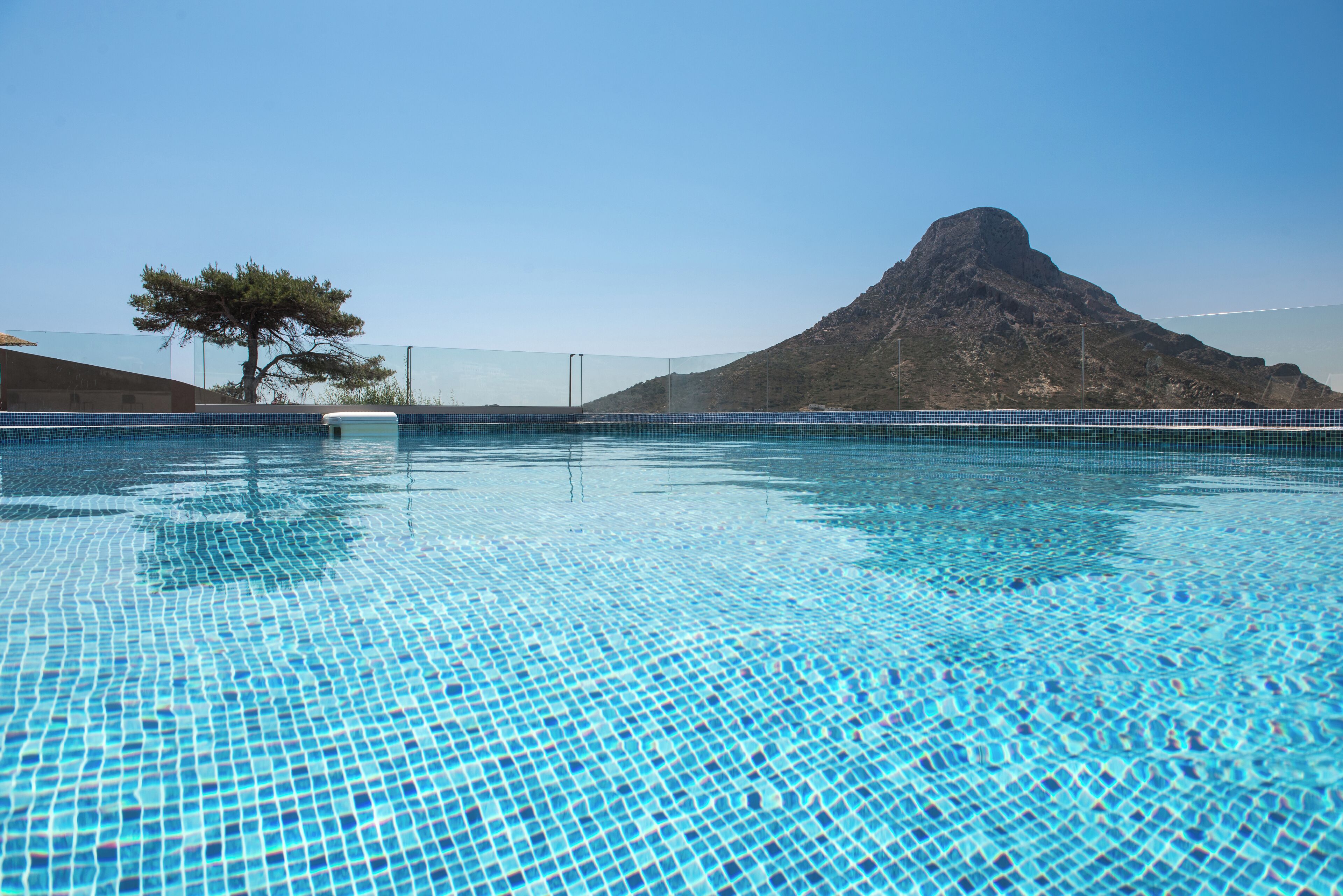 A clear blue pool with a mountain in the background.