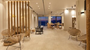 Un interior moderno con muebles de mimbre, un separador de madera y vista al mar.