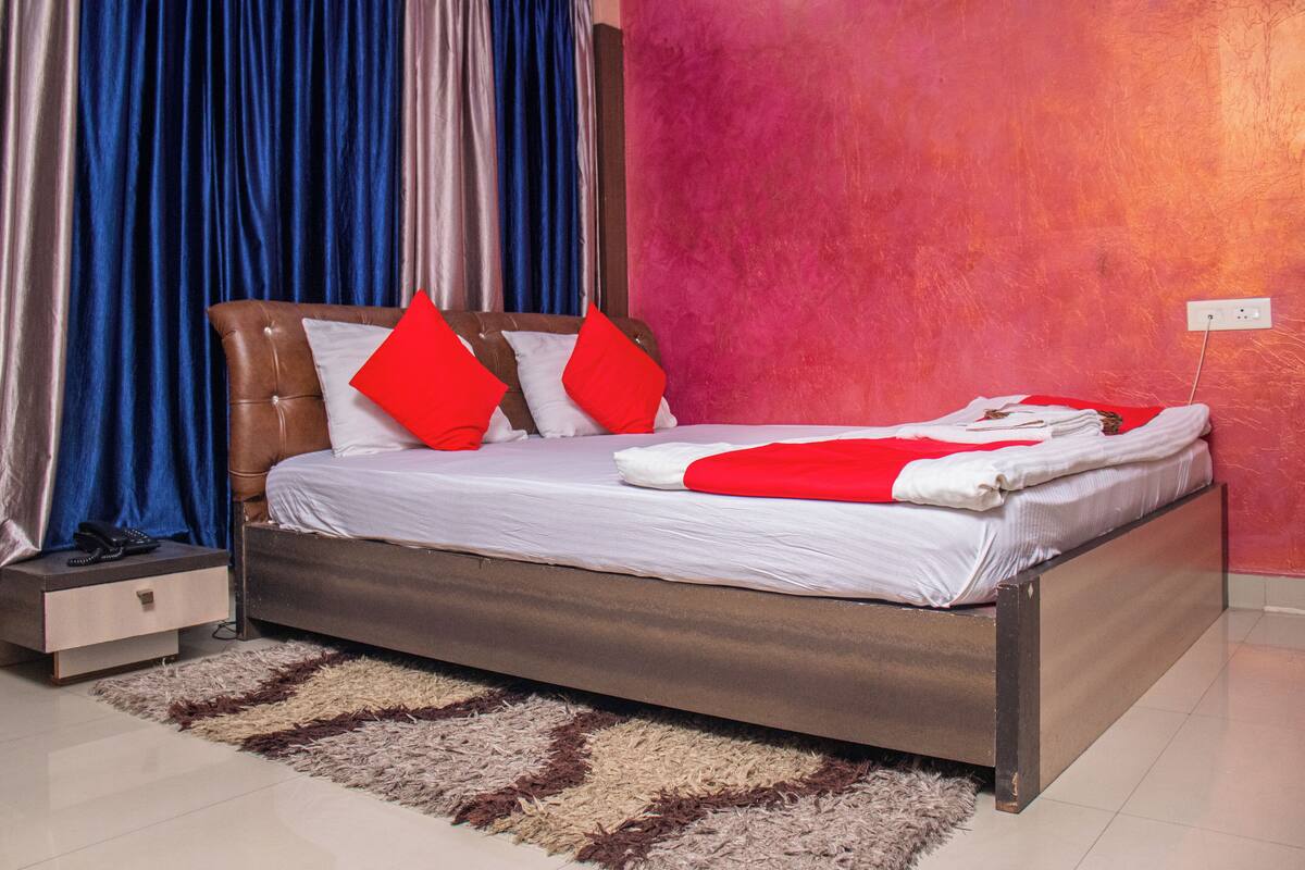Une chambre à coucher moderne avec un lit, une table de chevet et une couverture rouge et blanche.