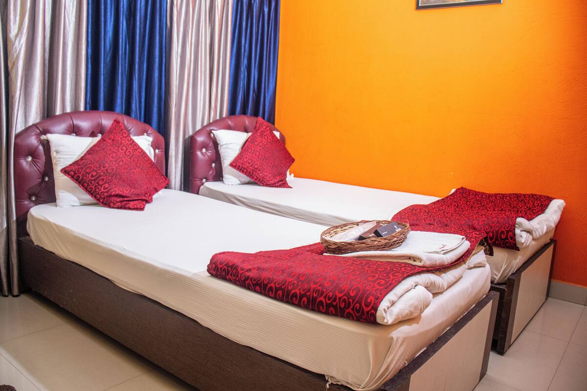 Une chambre d’hôtel avec deux lits, chacun recouvert d’une couverture à motifs rouges et agrémenté d’oreillers assortis.