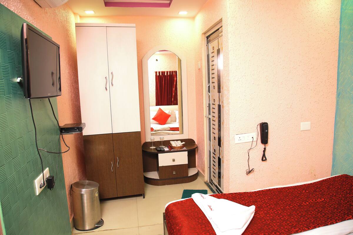 Une chambre d’hôtel équipée d’un lit, d’une armoire, d’un bureau avec un miroir, d’une poubelle et d’un téléphone.