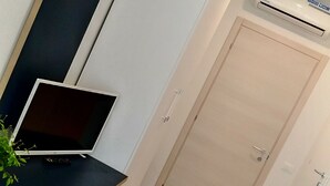 A modern room with a flat-screen TV, a laptop, a white wardrobe, and a built-in air conditioning unit. - Locazione Turistica Dal Degan (San Bonifacio)