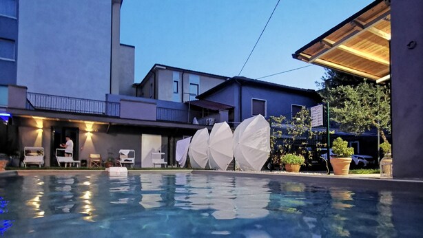 A swimming pool with a clear view of the surrounding buildings and a night sky. - Locazione Turistica Dal Degan (San Bonifacio)