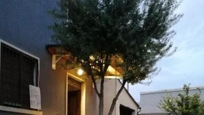 A building with a gravel driveway, a well-maintained lawn, and a large tree in front. - Locazione Turistica Dal Degan (San Bonifacio)
