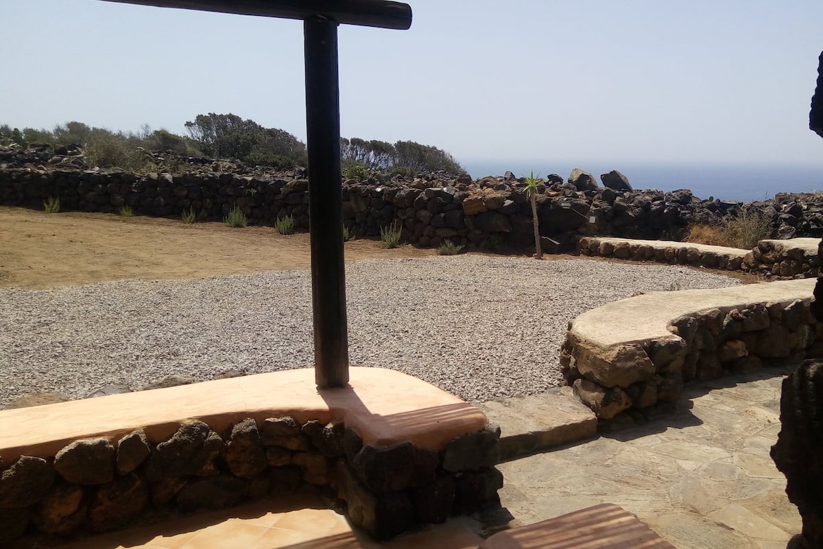 A stone pathway leading to a seating area with a view of the ocean.