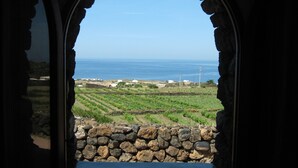 A stone wall with a view of a coastal landscape, including fields and buildings.