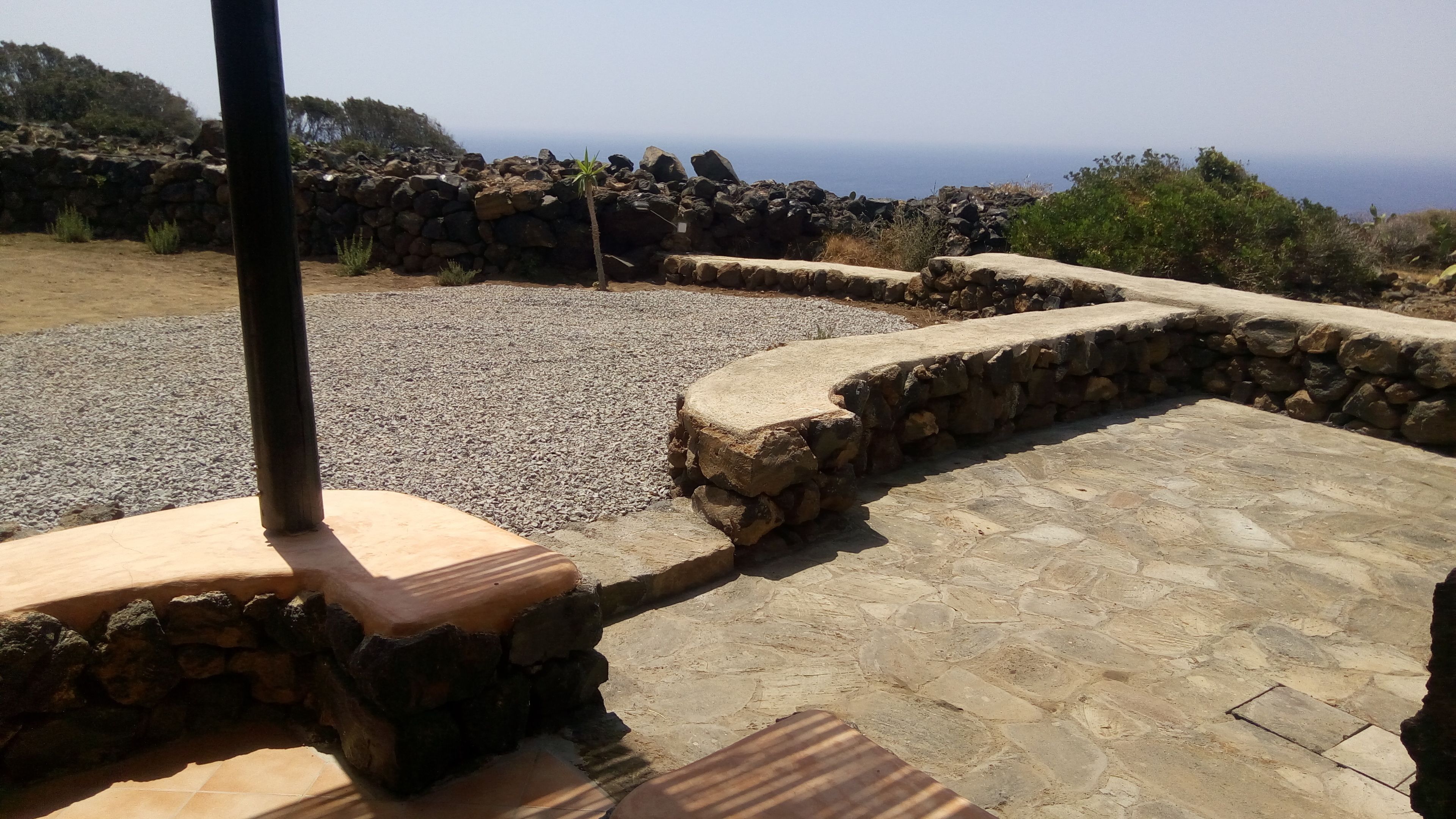 A stone patio with a wooden bench and a stone wall.
