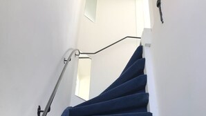 Una escalera con barandilla y un interruptor de luz en la pared.
