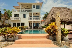 A two-story hotel with a pool, balconies, and a thatched-roof structure. - Villa Jammin Gecko (Placencia)