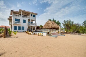 A beachfront hotel with multiple balconies, a swimming pool, and a thatched-roof structure. - Villa Jammin Gecko (Placencia)