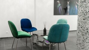 A modern room with a round glass table surrounded by three chairs in green, blue, and teal. - Hotel Birsighof (Basel)